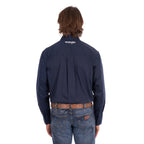 A man from behind wearing a navy blue Wrangler Men's Flex Logo Long Sleeve Shirt (XCP1155359) with a white logo printed vertically on the left sleeve, paired with blue jeans and a Wrangler Onyx Belt (X6S1969BLT), against a plain white background.