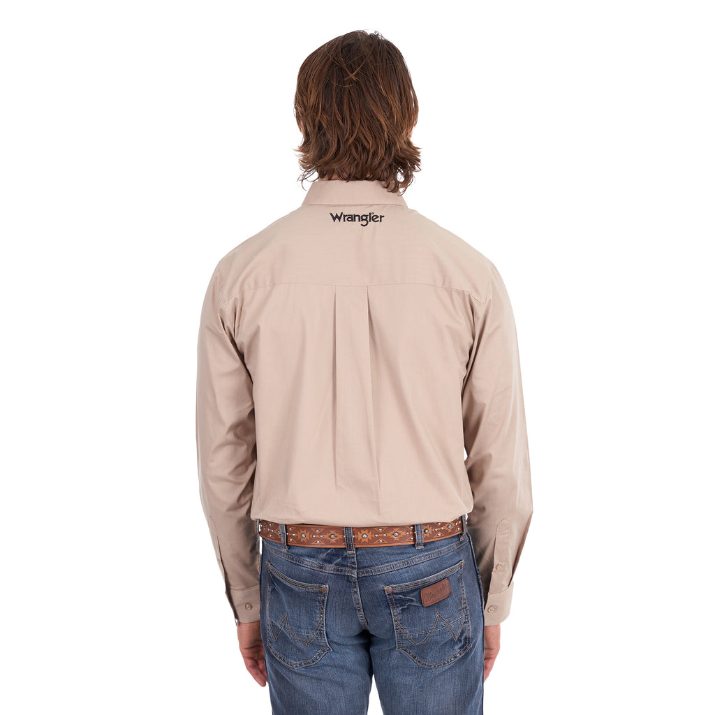 A man from behind wearing a sand Wrangler Men's Flex Logo Long Sleeve Shirt (XCP1155359) with a black logo printed vertically on the left sleeve, paired with blue jeans and a Wrangler Onyx Belt (X6S1969BLT), against a solid white background.