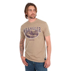 A man wearing a tan Wrangler Men's James Short Sleeve T-Shirt (XCP1557686) with a vintage-style graphic on the chest, paired with blue jeans, photographed against a solid white background.