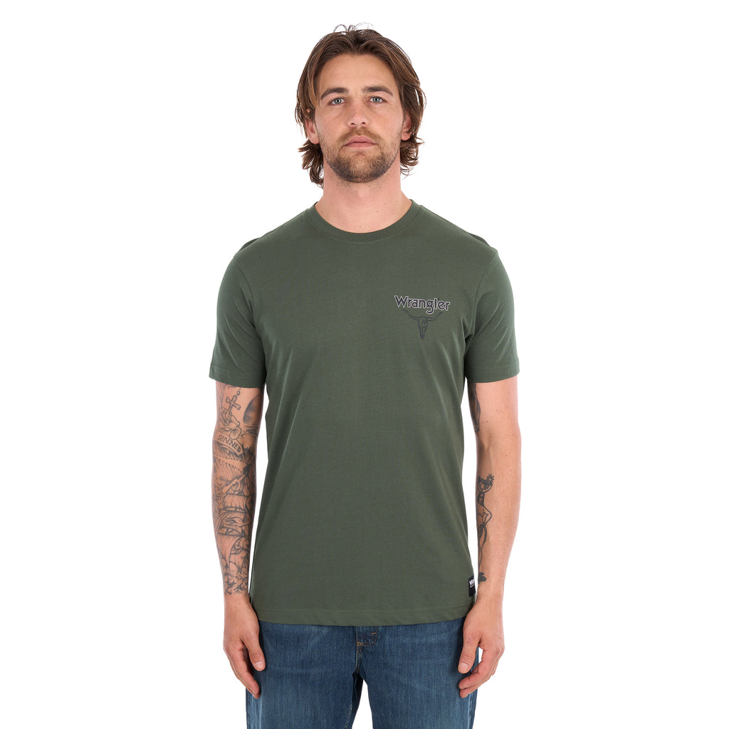 A man wearing a cypress green Wrangler Men's Jay Short Sleeve T-shirt (XCP1557683) with a small Wrangler logo on the left chest, paired with blue jeans, photographed against a solid white background.