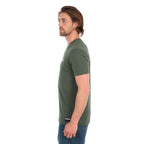 A man in profile wearing a cypress green Wrangler Men's Jay Short Sleeve T-shirt (XCP1557683) with a small Wrangler logo on the left chest, paired with blue jeans, photographed against a solid white background.