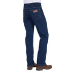 Rear three-quarter view of a man wearing a pair of original rinse dark blue Wrangler Men's Regular Bootcut Jeans (XLR1201032) with brown boots against a plain white background.