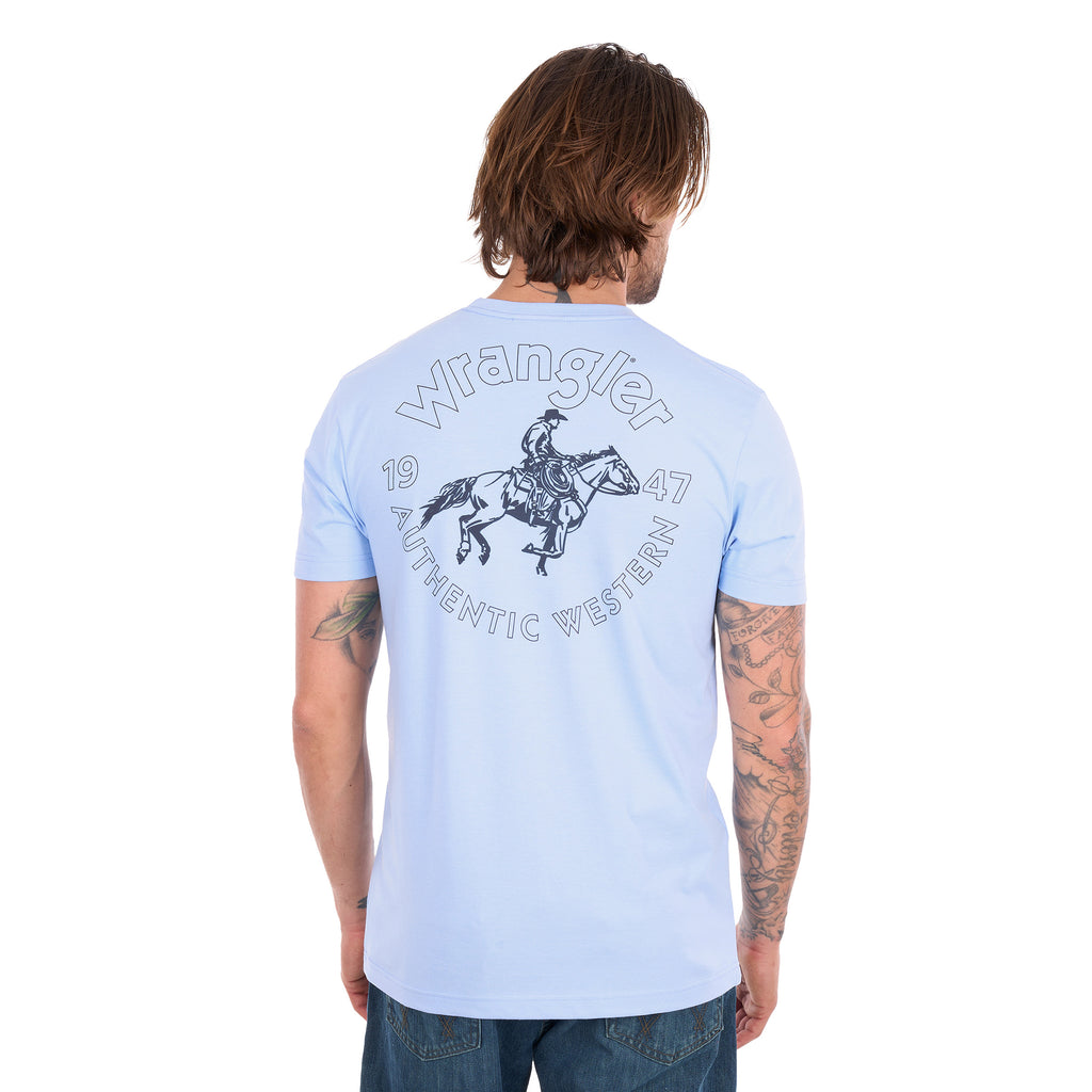 A man from behind wearing a light blue Wrangler Men's Steve Short Sleeve Tee (X6S1557597) with a large circular graphic on the back, paired with blue jeans, photographed against a solid white background.