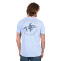 A man from behind wearing a light blue Wrangler Men's Steve Short Sleeve Tee (X6S1557597) with a large circular graphic on the back, paired with blue jeans, photographed against a solid white background.