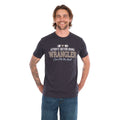 A man wearing a charcoal Wrangler Men's Tim Short Sleeve Tee (X6S1557696) with a Wrangler graphic on the chest, paired with blue jeans, standing against a plain white background.