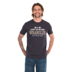 A man wearing a charcoal Wrangler Men's Tim Short Sleeve Tee (X6S1557696) with a Wrangler graphic on the chest, paired with blue jeans, standing against a plain white background.