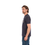 A man in profile wearing a charcoal Wrangler Men's Tim Short Sleeve Tee (X6S1557696) with a Wrangler graphic on the chest, paired with blue jeans, standing against a plain white background.