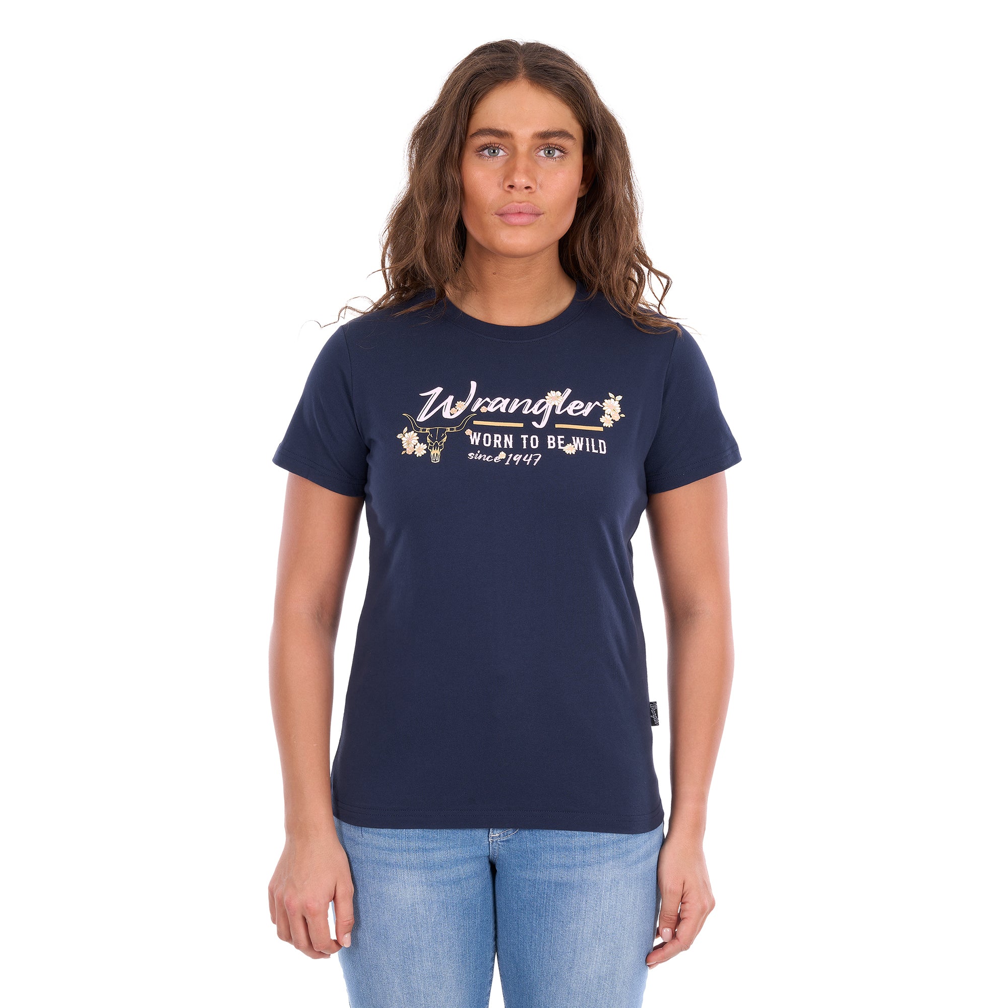 A woman modelling a navy blue Wrangler Belle Tee (X6S2598643) with a yellow and white Wrangler graphic print on the chest, paired with light blue jeans, against a plain white background.