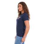 A woman viewed in profile modelling a navy blue Wrangler Belle Tee (X6S2598643) with a yellow and white Wrangler graphic print on the chest, paired with light blue jeans, against a plain white background.