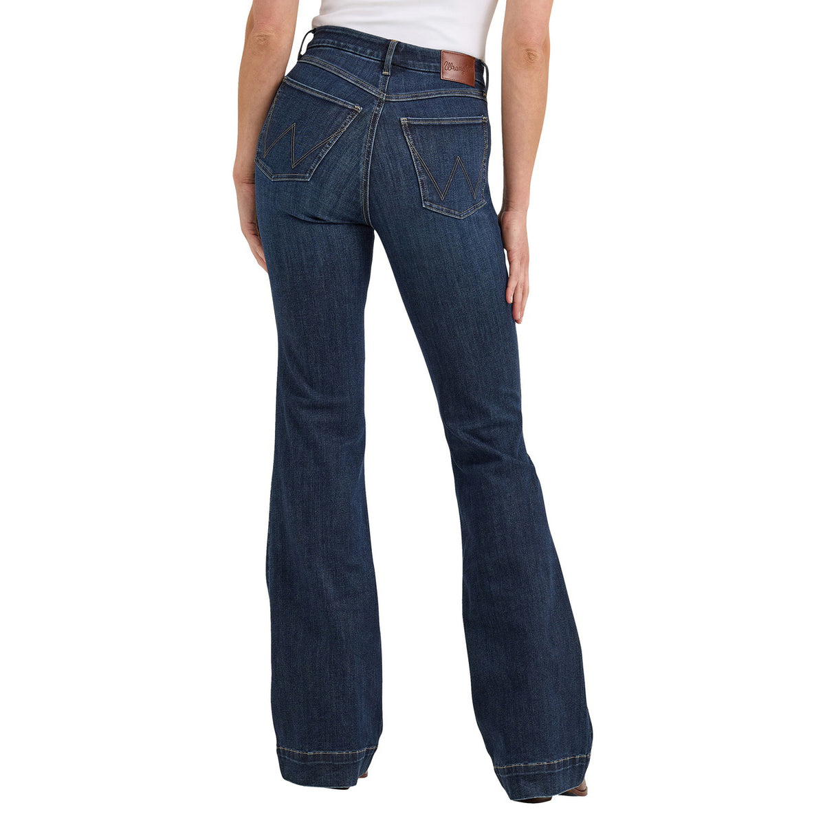 A back view of a woman modelling a pair of Alexandra blue Wrangler Women's Bespoke Hi Rise Trouser Jeans (112367600) with a slight flare, paired with a white top and brown boots, against a plain white background.