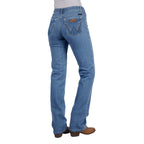 Rear view of a woman wearing faded blue Wrangler Women's Chara Willow Jeans (XCP2251216) with decorative stitching on the back pockets and brown cowboy boots, shown against a plain white background.