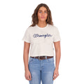A woman modelling a Wrangler Women's Cindy Crop Short Sleeve T-Shirt (XCP2596647) in cream with a navy blue 'Wrangler' rope logo across the chest, paired with blue jeans and a tan Wrangler Western Molly Belt (XCP2919BLT), against a plain white background.