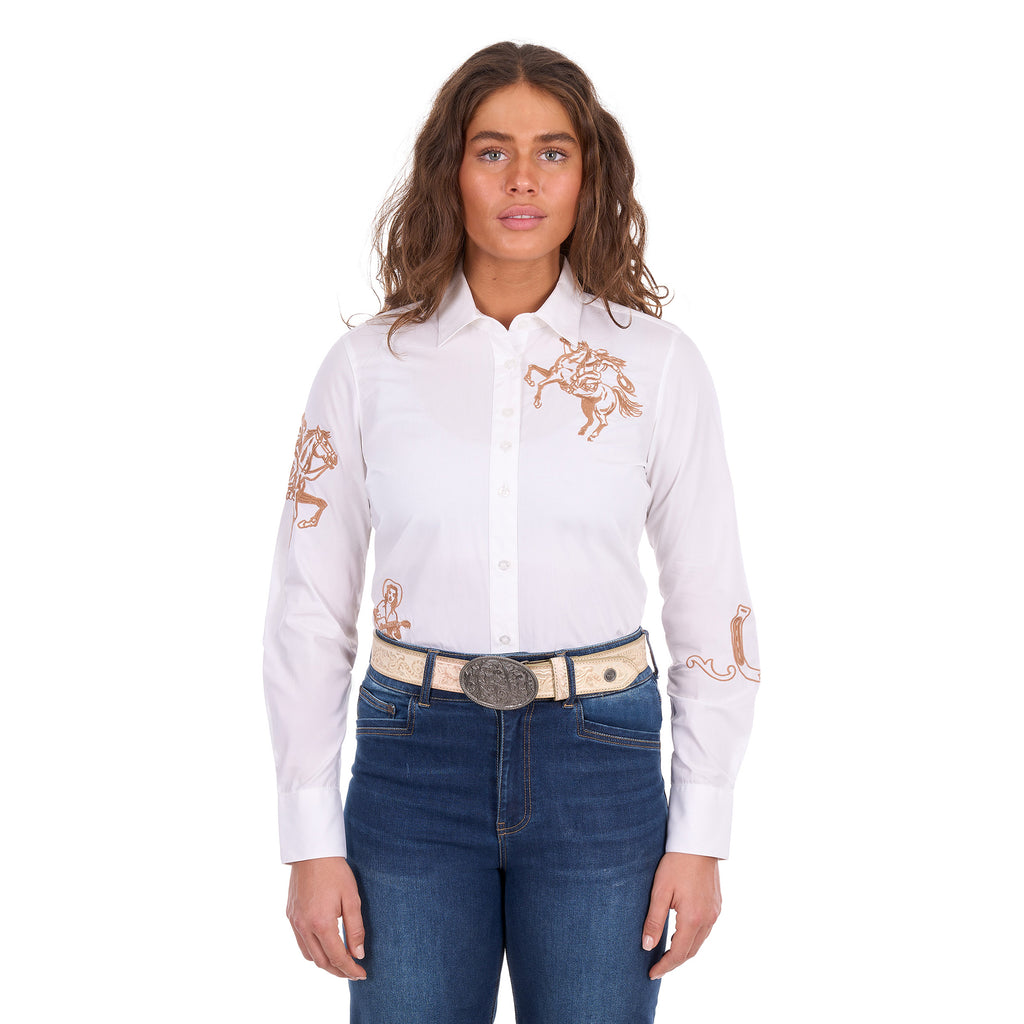 A woman modelling a white Wrangler Women's Darcy Long Sleeve Shirt (X6S2100606) with embroidered horse motifs on the chest and sleeves, paired with blue jeans and a Wrangler Zola Belt (XCP2918BLT) in Stone, against a plain white background.