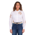 A woman modelling a white Wrangler Women's Darcy Long Sleeve Shirt (X6S2100606) with embroidered horse motifs on the chest and sleeves, paired with blue jeans and a Wrangler Zola Belt (XCP2918BLT) in Stone, against a plain white background.