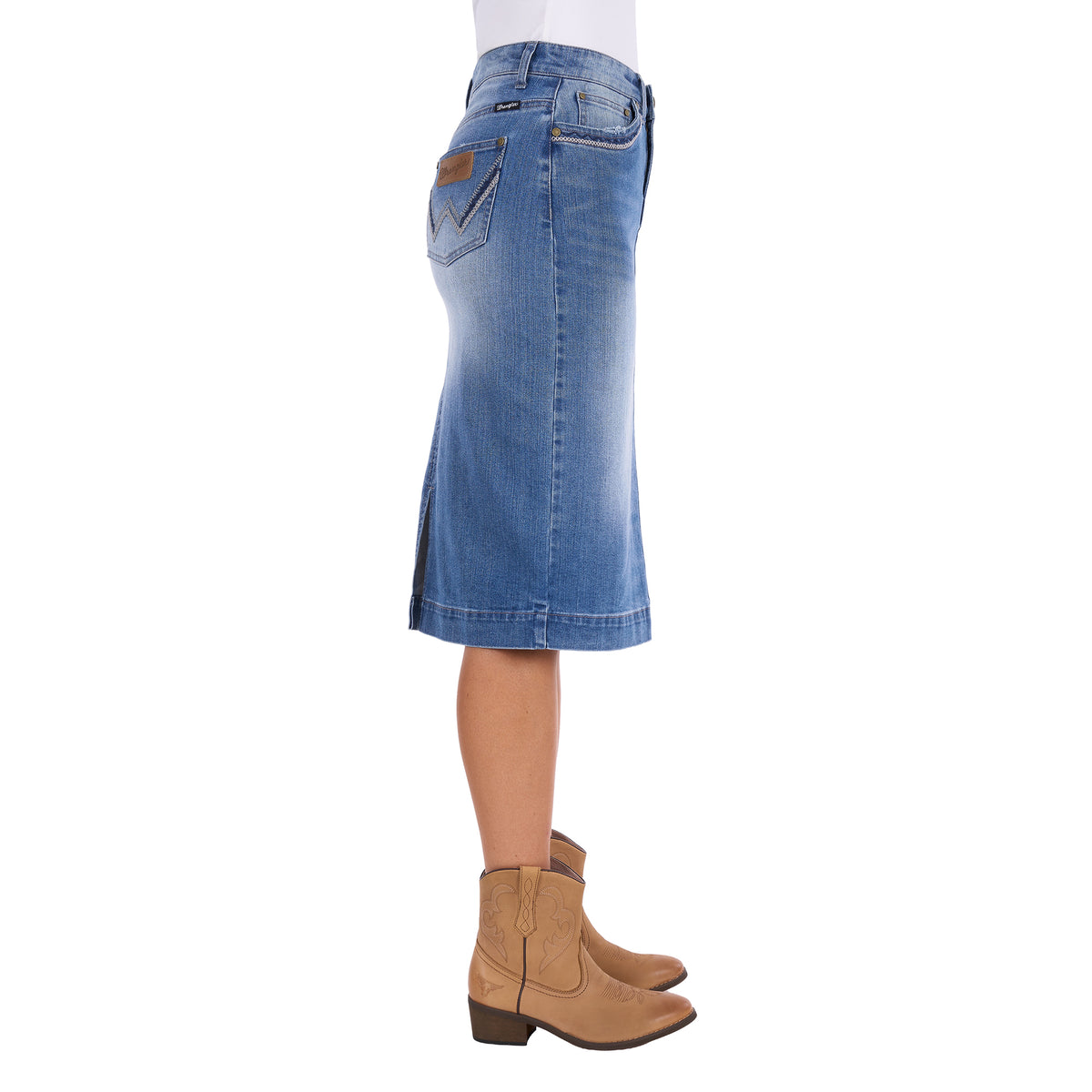 A Wrangler Women's Emmie Denim Skirt (X6S2410724) in light Kora Blue with embroidered pockets shown on a model from the waist down, photographed from the side, paired with tan cowboy boots against a plain white background.