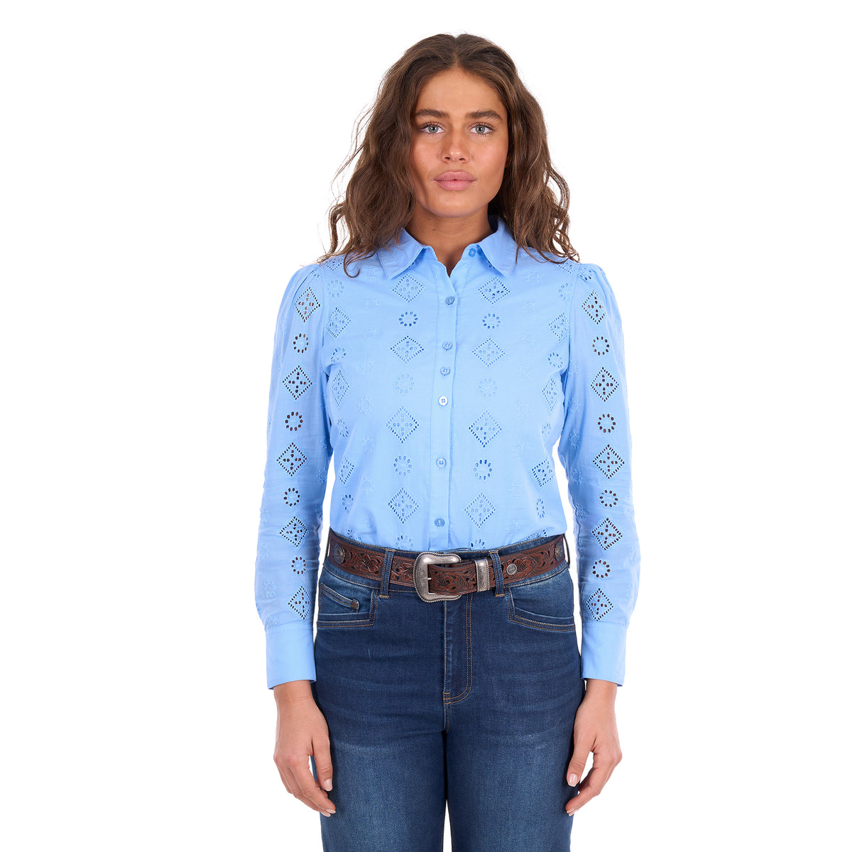 A woman modelling a cornflower blue Wrangler Women's Fleur Long Sleeve Shirt (X6S2104600) with embroidered Aztec inspired patterns, paired with dark blue jeans and a tan Wrangler Molly Belt (XCP2919BLT), against a plain white background.