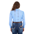 A woman viewed from behind modelling a cornflower blue Wrangler Women's Fleur Long Sleeve Shirt (X6S2104600) with embroidered Aztec inspired patterns, paired with dark blue jeans and a tan Wrangler Molly Belt (XCP2919BLT), against a plain white background.
