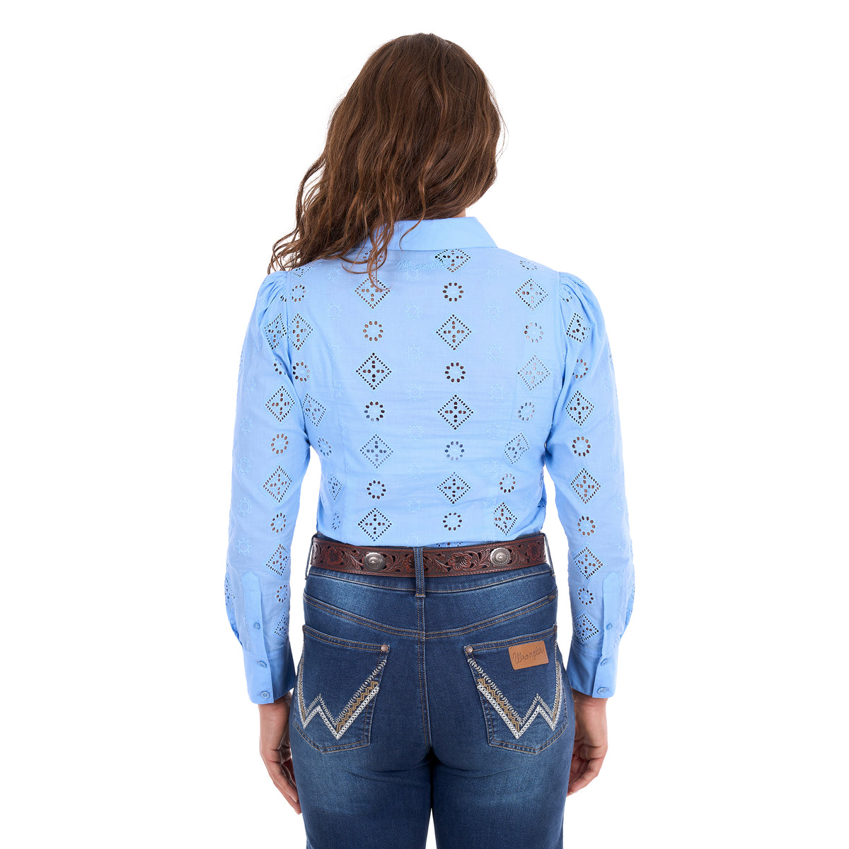 A woman viewed from behind modelling a cornflower blue Wrangler Women's Fleur Long Sleeve Shirt (X6S2104600) with embroidered Aztec inspired patterns, paired with dark blue jeans and a tan Wrangler Molly Belt (XCP2919BLT), against a plain white background.