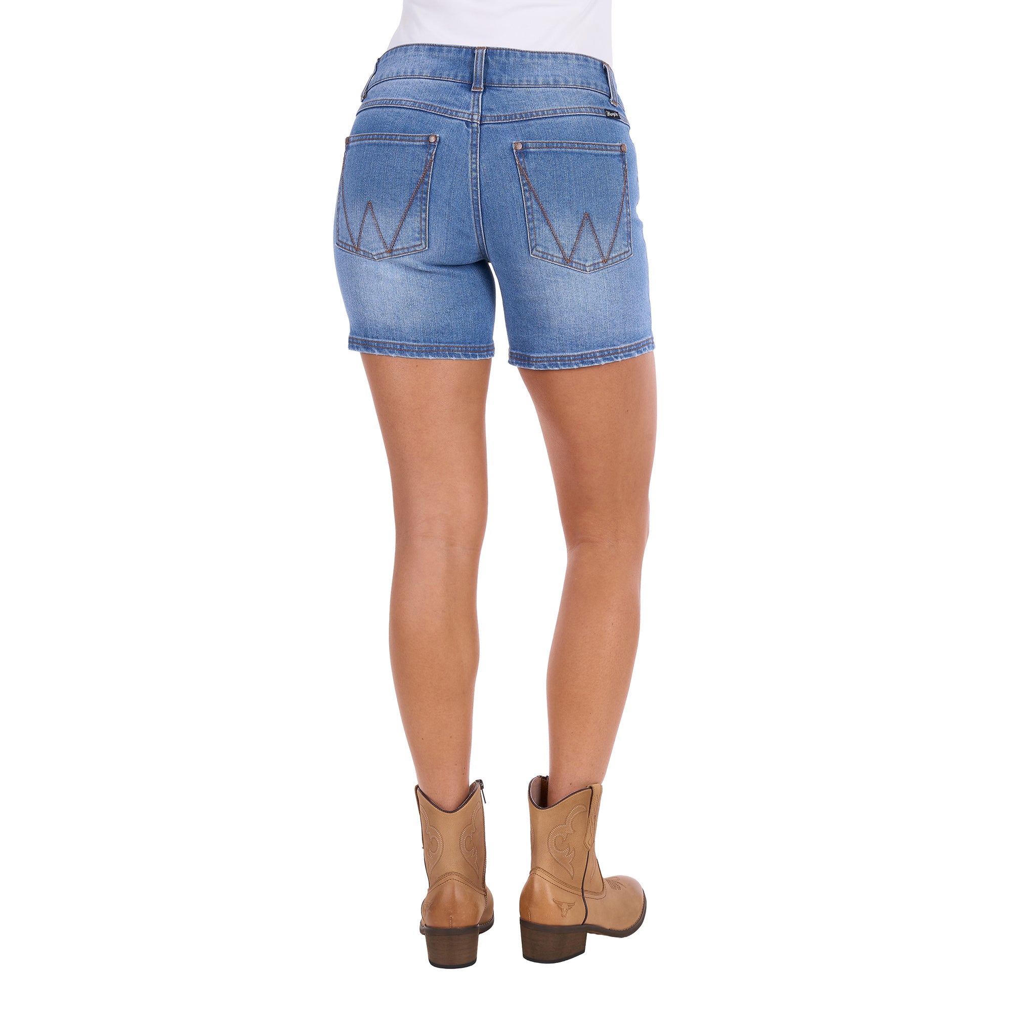 Rear view of a model wearing faded blue Wrangler Women's Gigi Mid Rise Denim Shorts (XCP2411717) with a western-style 'W' patch on the back pocket, paired with tan cowboy boots against a white background.