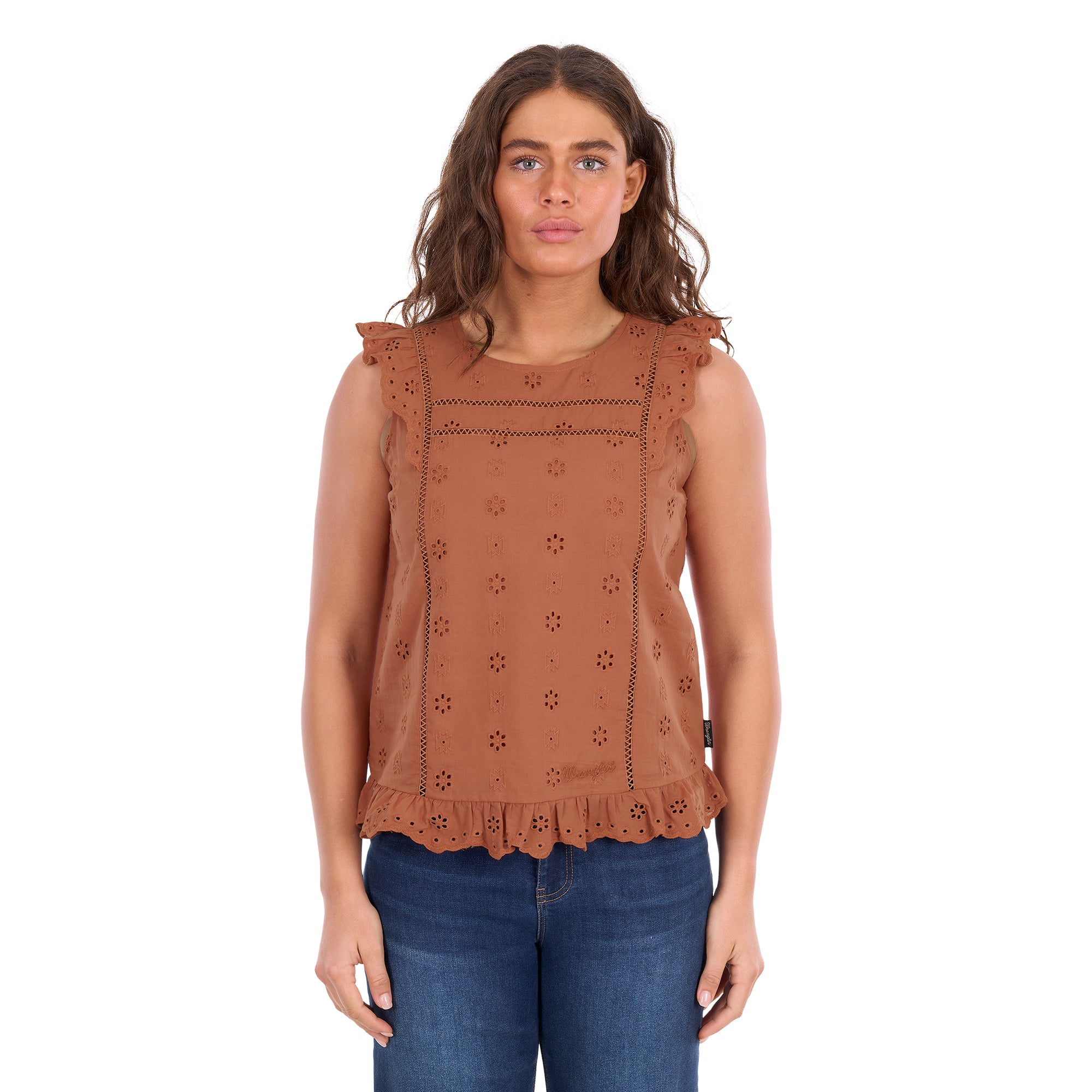 A woman modelling a copper Wrangler Women's Grace Sleeveless Blouse (X6S2502615) with eyelet embroidery and a ruffled hem, paired with blue jeans, against a plain white background.