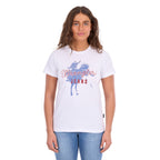 A woman modelling a white Wrangler Women's Gwen Tee (X6S2598635) t-shirt with a blue and red graphic on the front, paired with blue jeans, against a plain white background.
