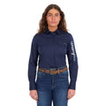 A woman modelling a navy Wrangler Women's Hazel Logo Long Sleeved Shirt (XCP2111608) with blue and white Wrangler script embroidery on the right sleeve, paired with blue jeans and a brown western belt against a plain white background.