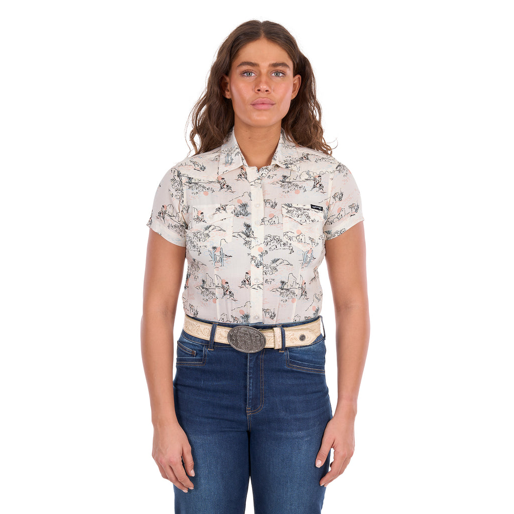 A woman modelling a cream Wrangler Women's Heidi Short Sleeve Shirt (X6S2102610) with a western novelty print, paired with blue jeans and a stone coloured Wrangler Zola Belt (XCP2918BLT), against a plain white background.