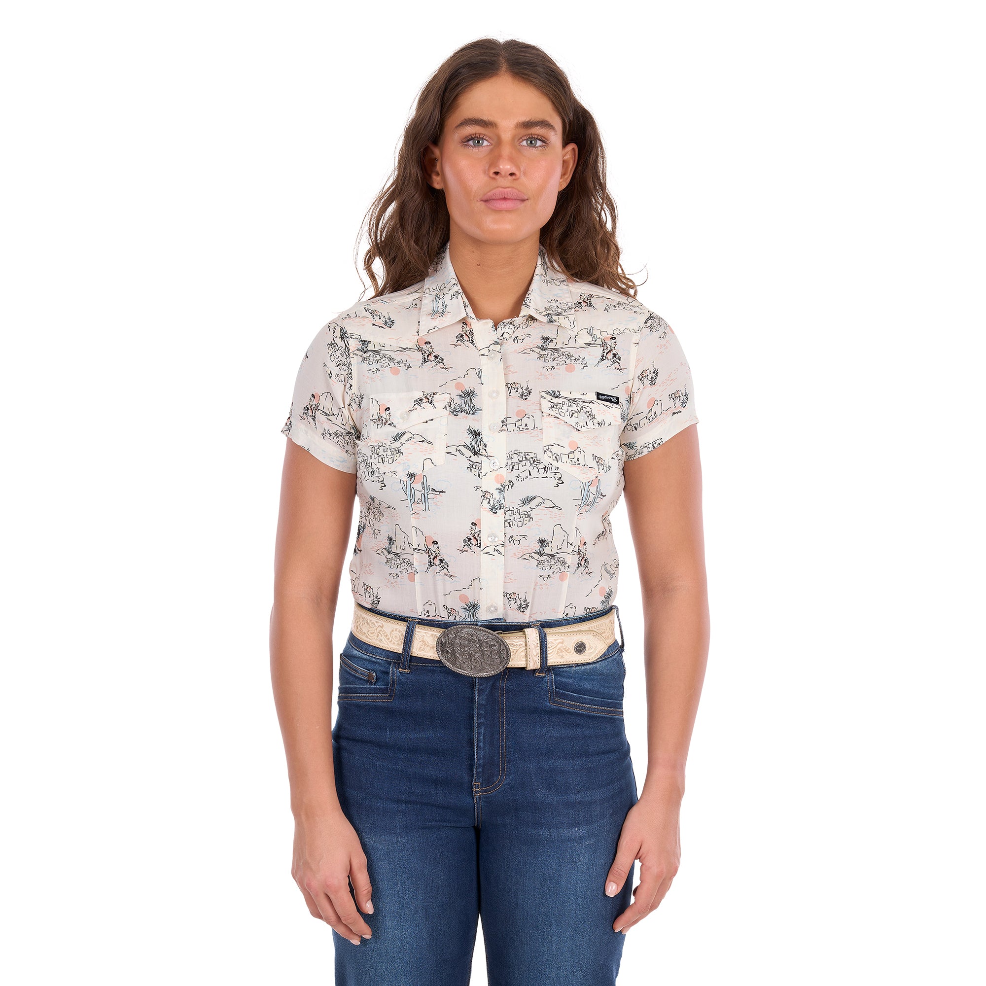 A woman modelling a cream Wrangler Women's Heidi Short Sleeve Shirt (X6S2102610) with a western novelty print, paired with blue jeans and a stone coloured Wrangler Zola Belt (XCP2918BLT), against a plain white background.