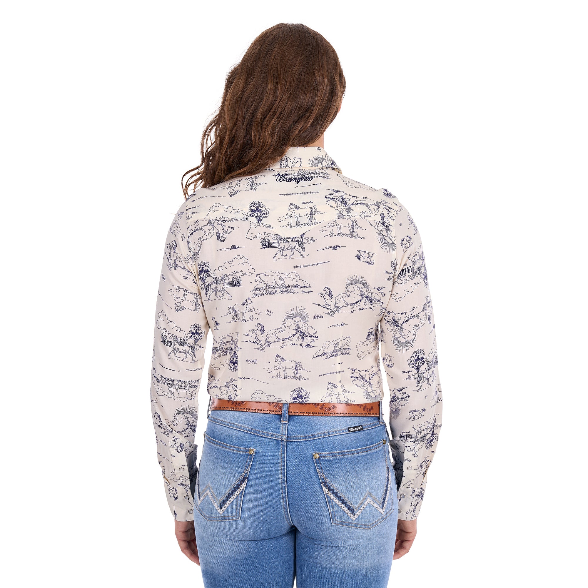 A woman viewed from behind, modelling a cream Wrangler Women's Ivory Long Sleeve Shirt (X6S2103602) with a western novelty print paired with kora blue Wrangler Women's Margo Trouser Jeans Willow (XCP2253710) and a Wrangler Silvie Belt (X6S2920BLT), against a plain white studio background.