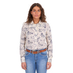 A woman modelling a cream Wrangler Women's Ivory Long Sleeve Shirt (X6S2103602) with a western novelty print paired with kora blue Wrangler Women's Margo Trouser Jeans Willow (XCP2253710) and a Wrangler Silvie Belt (X6S2920BLT), against a plain white studio background.