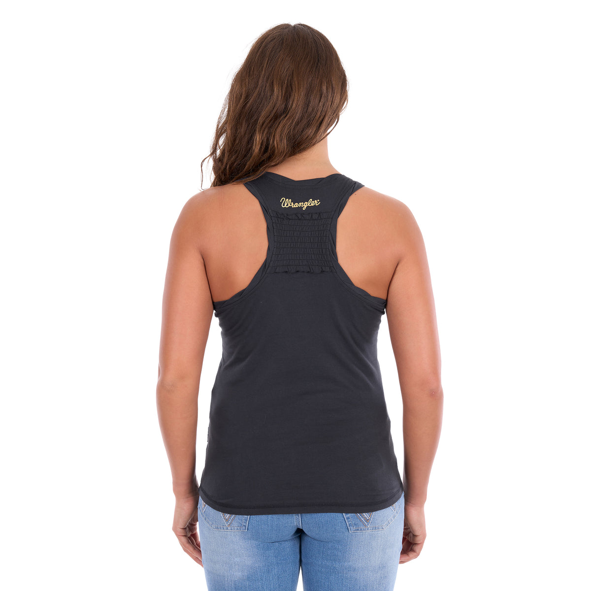 A woman photographed the back modelling a charcoal Wrangler Women's Jasmine Tank (X6S2508648) with racerback, featuring 'Wrangler' back neck logo print and a shirred back panel, paired with light blue jeans, against a plain white background.