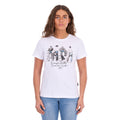 A woman modelling a white graphic Wrangler Women's Josie Short Sleeve T-Shirt (XCP2598641) with a black and white print of riders on a fence and the text 'Wrangler Butts Drive Me Nuts' on the front, paired with blue jeans against a plain white background.