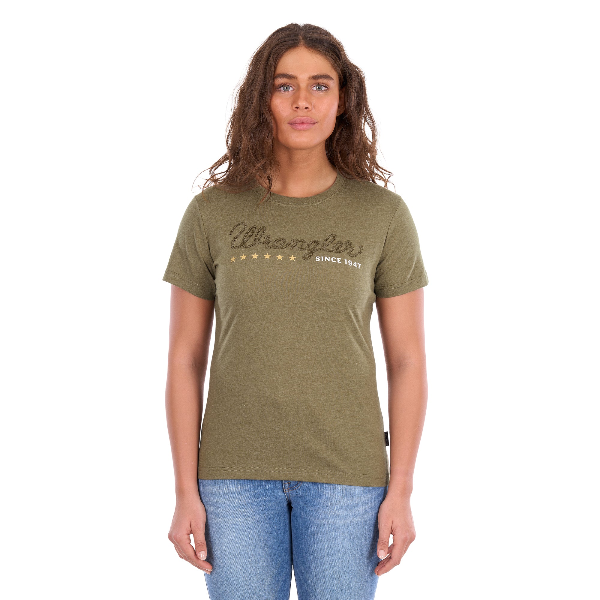 A woman modelling a Wrangler Women's Lucy Tee (XCP2598633) Khaki Marle with an embroidered script logo and gold stars on the chest, paired with blue jeans against a plain white background.