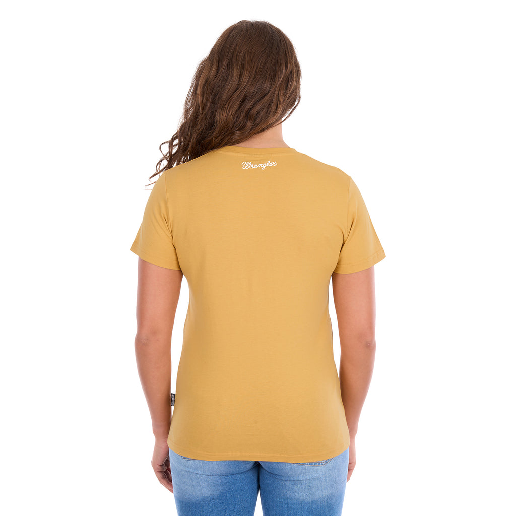 A woman modelling a sunset yellow Wrangler Women's Macie Tee (X6S2598637) with a back neck Wrangler logo, worn with blue jeans, set against a plain white background.