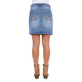 A faded blue Wrangler Women's Maisy Denim Skirt (XCP2409723) with decorative embroidery on the back pockets, shown on a model from the rear wearing tan cowboy boots against a white background.