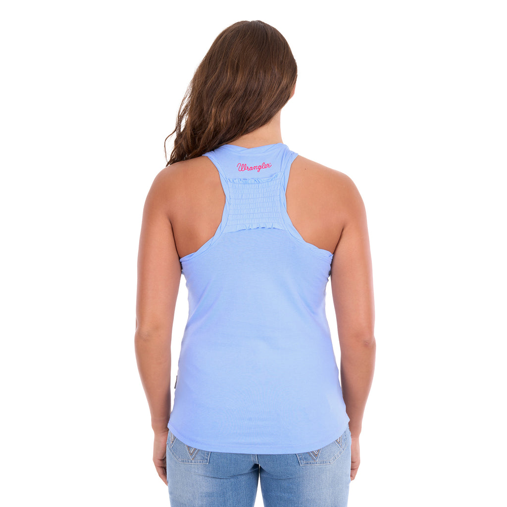 A woman viewed from the back wearing a light blue Wrangler Womens Maya Tank (X6S2508649) racerback top with a shirred panel and a small pink 'Wrangler' logo on the inner neck, paired with light blue jeans against a white background.