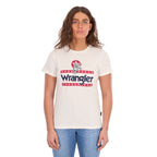 A woman modelling a Wrangler Women's Nora Short Sleeve Tee (XCP2598636) in cream, featuring a red, white, and navy blue graphic logo on the chest, paired with blue jeans against a plain white background.