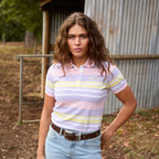 A woman modelling a yellow and lavender Wrangler Women's Quinn Short Sleeve Polo (X6S2514626) in an ourdoor rural setting in front of a shed.