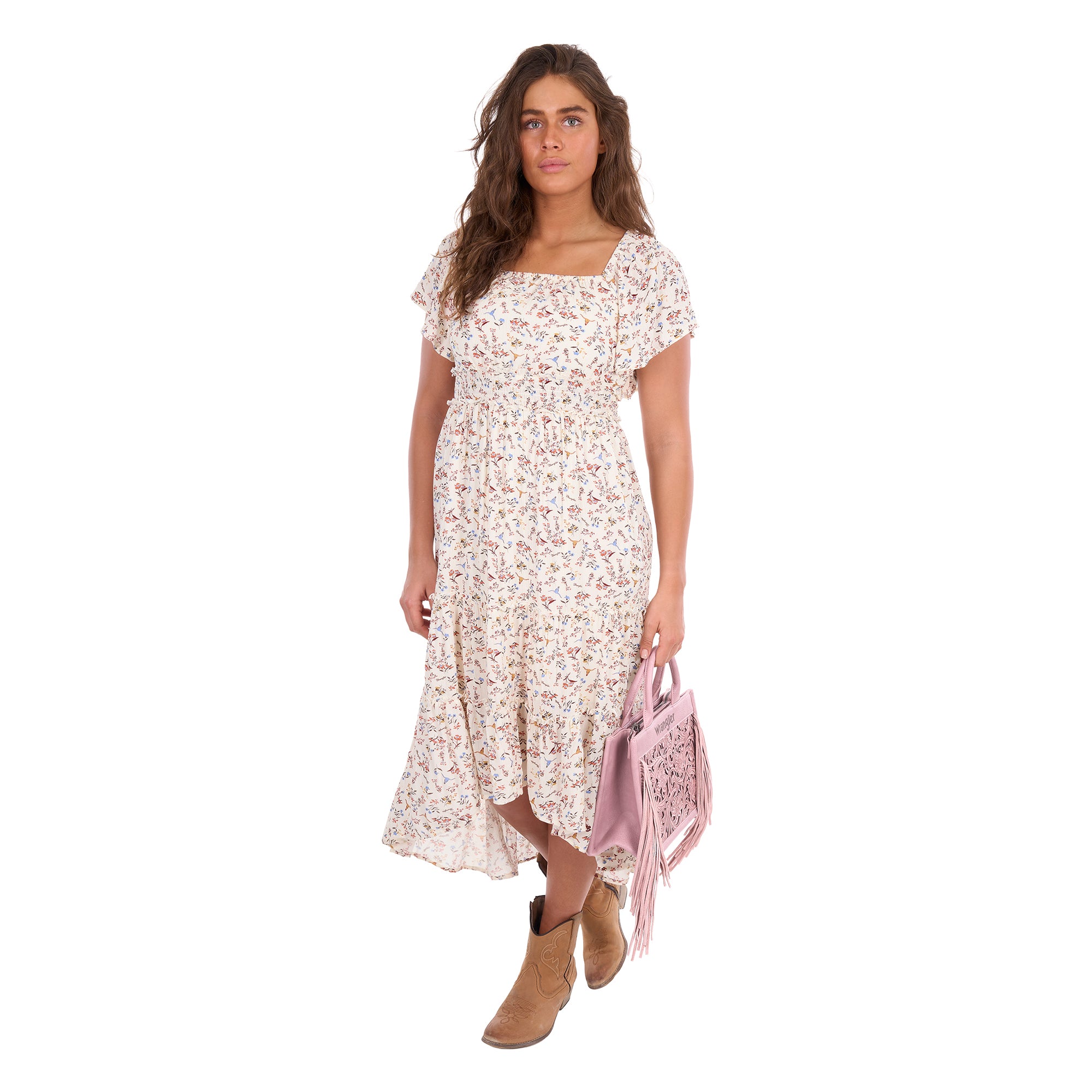A woman modelling a cream Wrangler Women's Renee Short Sleeved Dress (X6S2407621) with a square neckline and a delicate western floral print on a light cream background, paired with brown ankle boots and a pink Wrangler Adelyn Bag (X6S2975BAG) set against a plain white background.