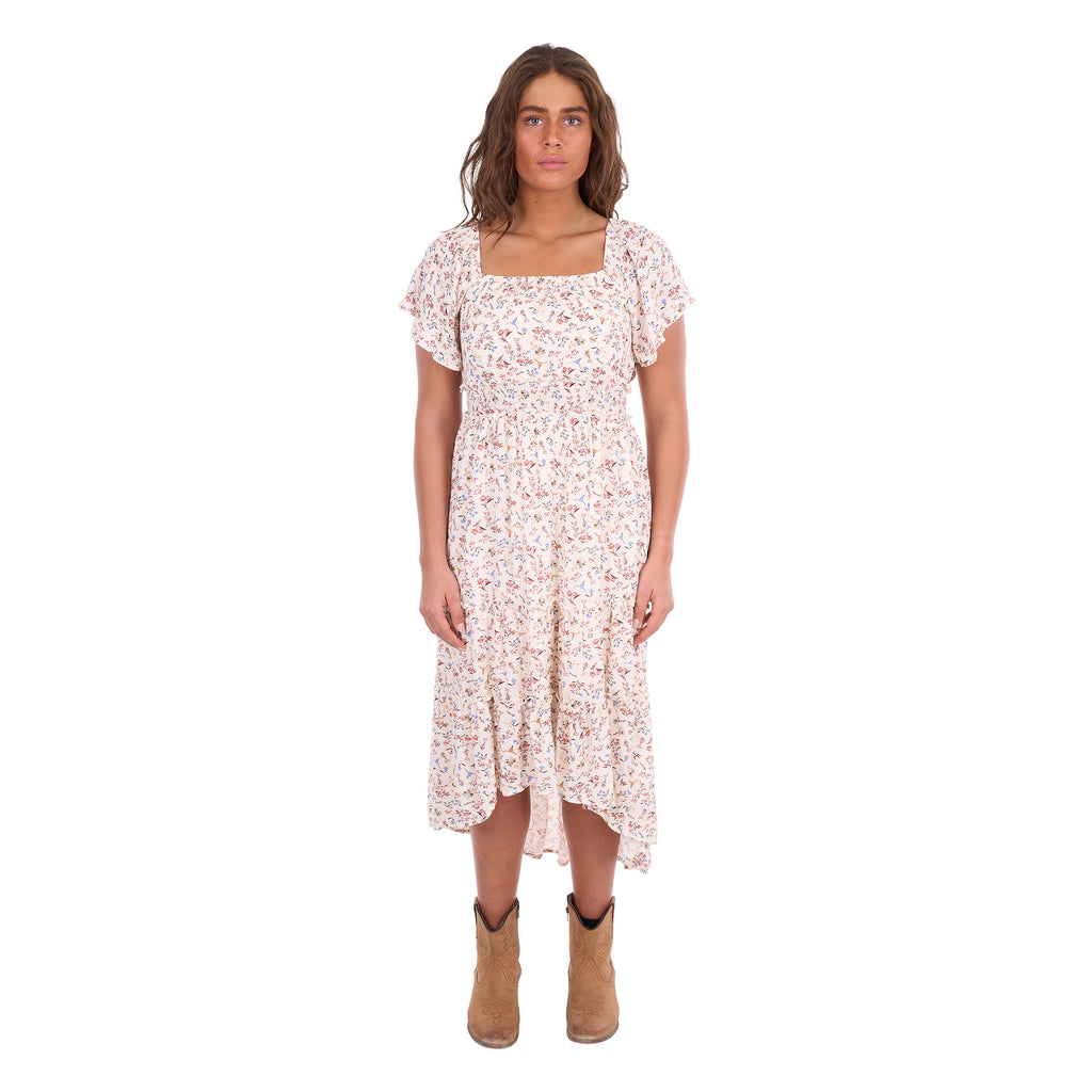 A woman modelling a cream Wrangler Women's Renee Short Sleeved Dress (X6S2407621) with a square neckline and a delicate western floral print on a light cream background, paired with brown ankle boots, set against a plain white background.