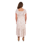 A woman modelling a cream Wrangler Women's Renee Short Sleeved Dress (X6S2407621) with a square neckline and a delicate western floral print on a light cream background, paired with brown ankle boots, set against a plain white background, photographed from behind.