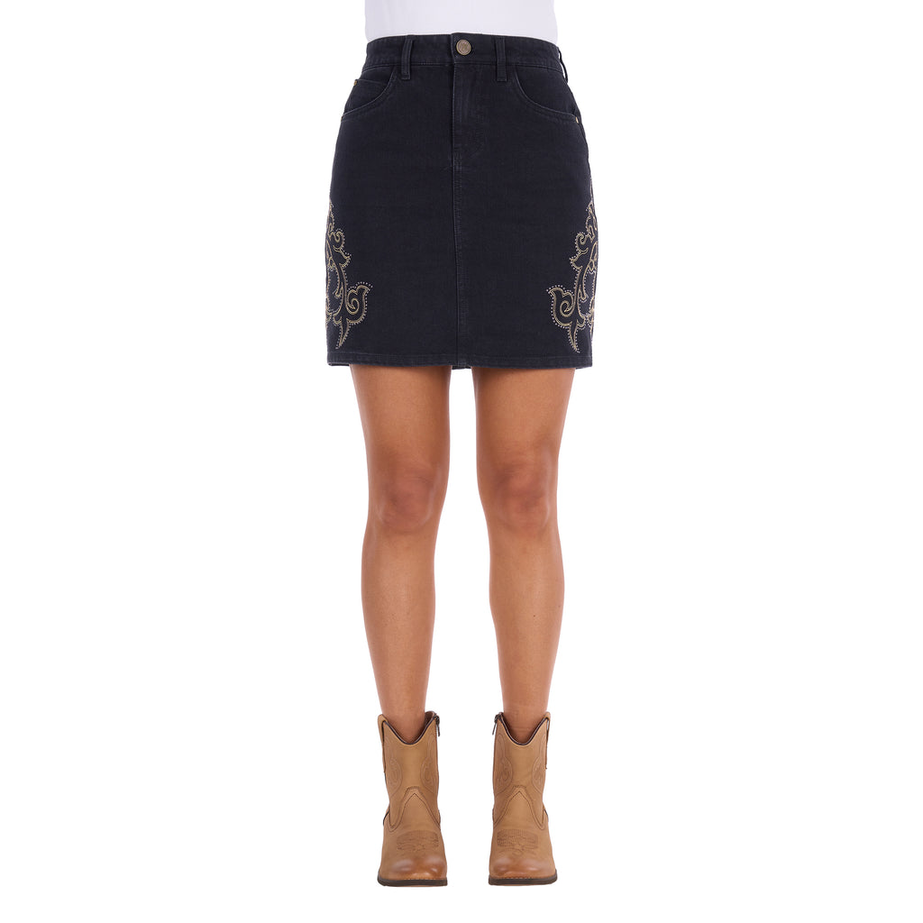 A black Wrangler Women's Rock Denim Mini Skirt (X6S2409725) with silver embroidered floral details on the sides, shown on a model from the waist down wearing tan cowboy boots against a white background.