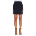 A black Wrangler Women's Rock Denim Mini Skirt (X6S2409725) with silver embroidered floral details on the sides, shown on a model from the waist down wearing tan cowboy boots against a white background.