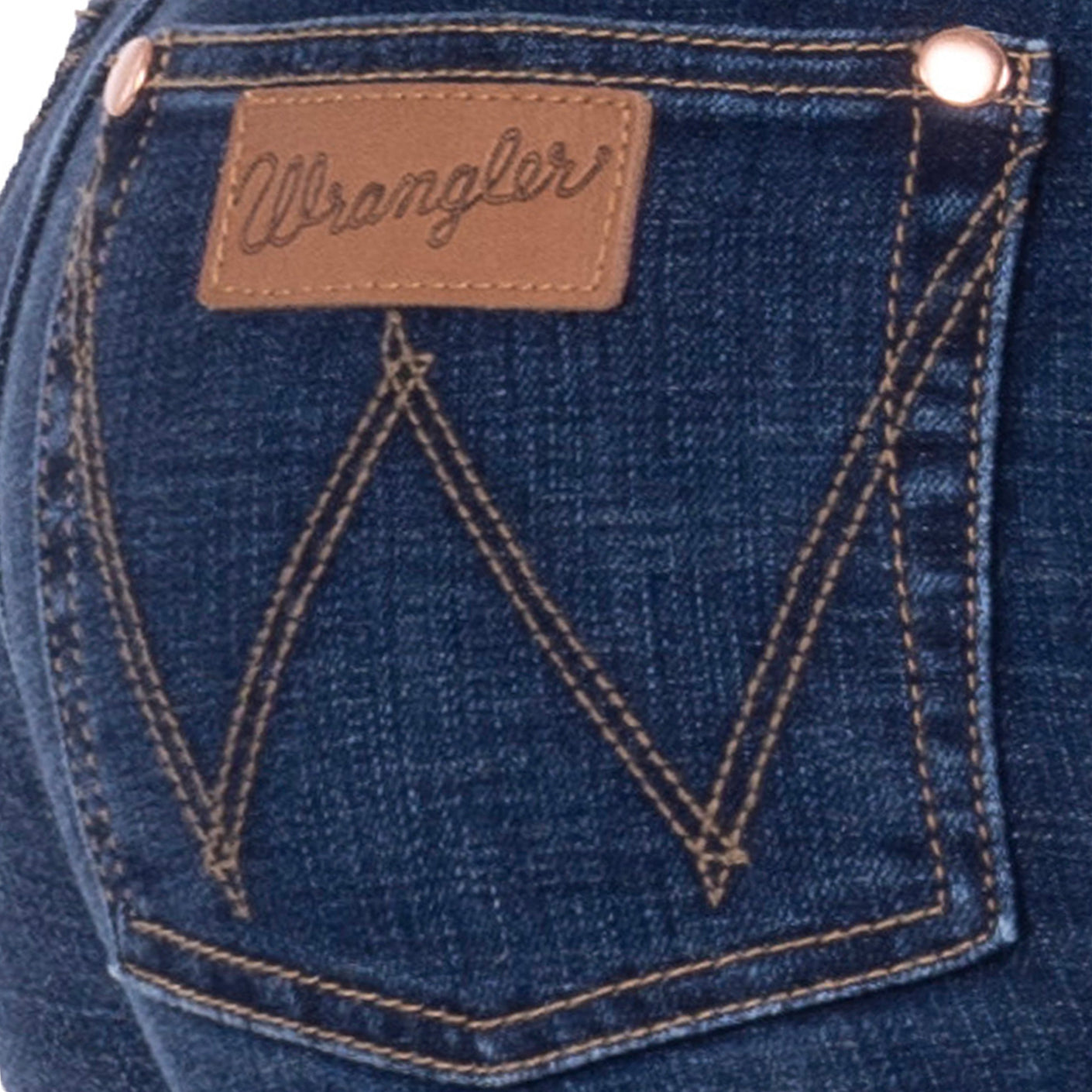 Close-up of the back pocket of a person wearing old indigo blue Wrangler Women's Sierra Skinny Jeans (XCP2238861), showing the brown leather brand patch, contrast stitching, and metal rivets on a white background.