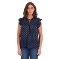 A woman modelling a navy blue Wrangler Women's Sofia Short Sleeve Blouse (X6S2503617) with a small repeating geometric pattern, ruffled cap sleeves, and a keyhole tie neckline, paired with blue jeans against a plain white background.